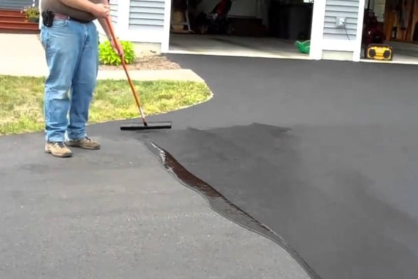 Worker applying sealcoating to a driveway